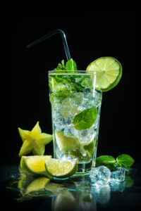Mojito cocktail with fresh lime and mint on dark background